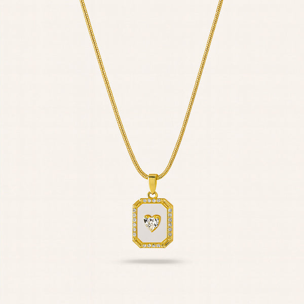 Gold necklace with a pendant featuring a heart design on a light beige background